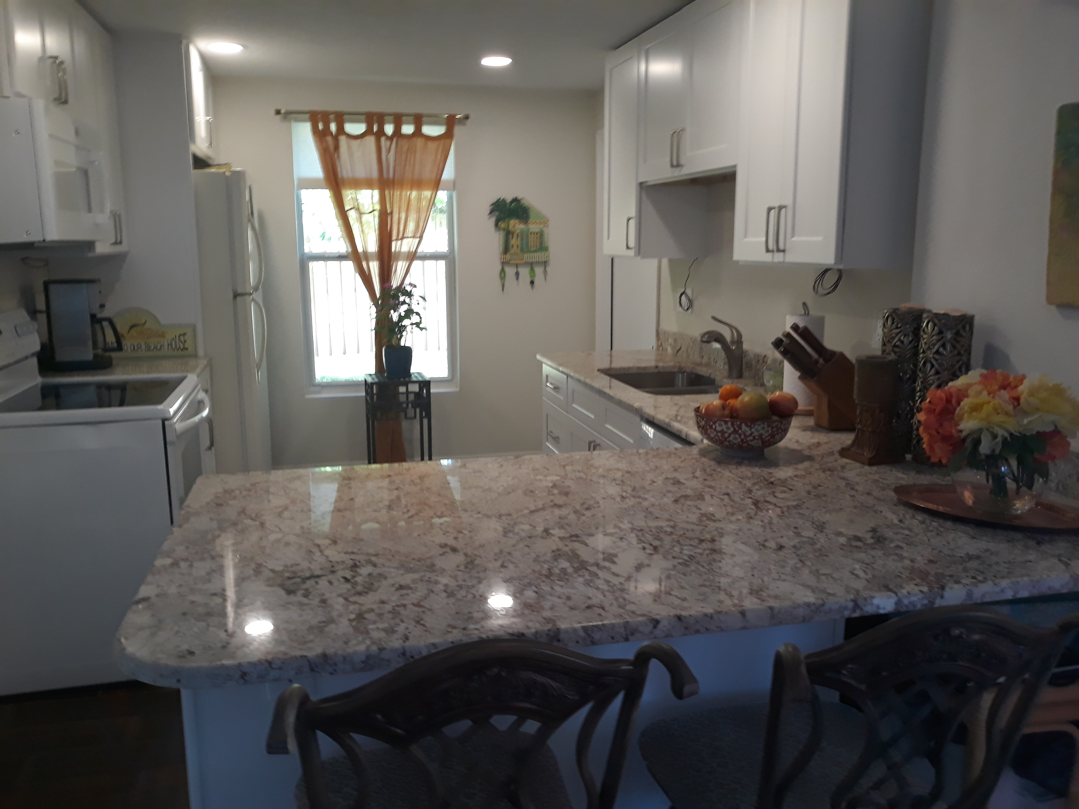 The kitchen has granite counter tops, white cabinets, and a view of the gardens.